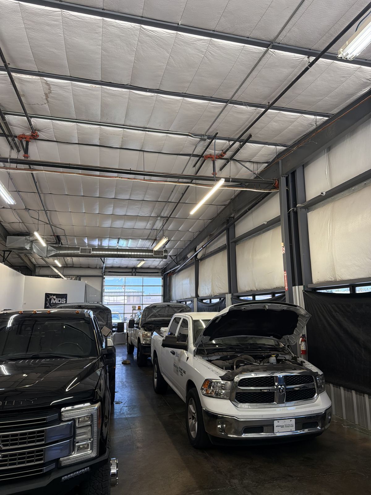 Two diesel trucks in the Modern Diesel Solutions shop bay